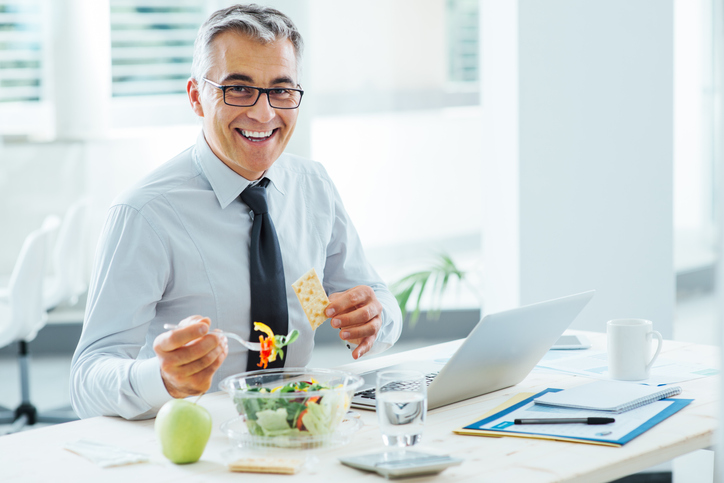 nutrition consultant eating a healthy lunch at his laptop